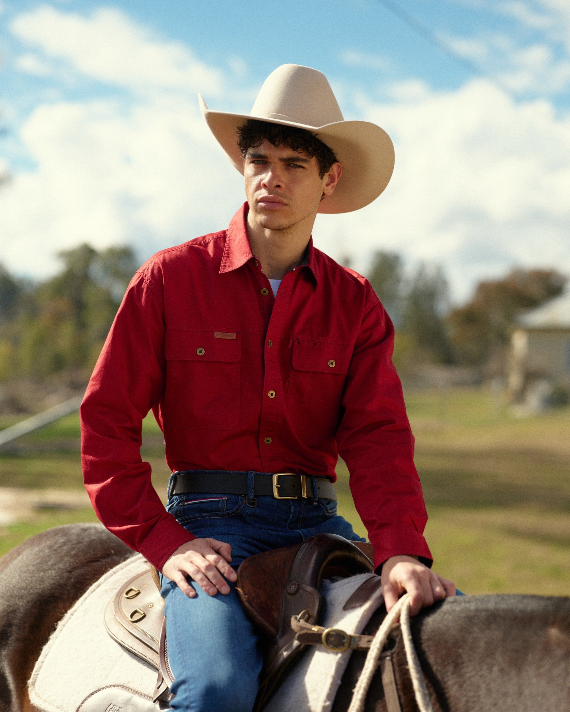 Man in S. Kidman Work Shirt riding a horse